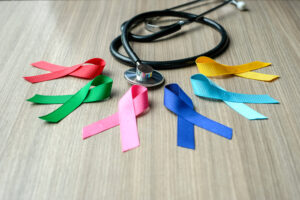 colorful awareness ribbons; blue, red, green, pink and yellow color on wooden background for cancer awareness and support