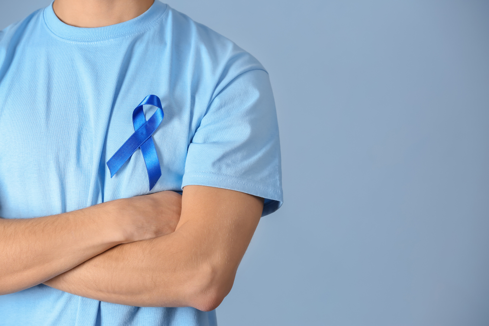 man in light blue shirt with prostate cancer blue awareness ribbon