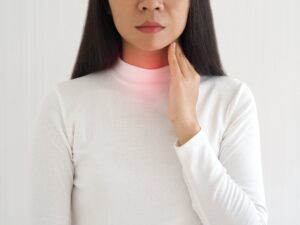 Woman touching her throat due to esophageal cancer.