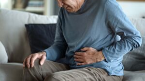older man holding his stomach in pain due to colon cancer.