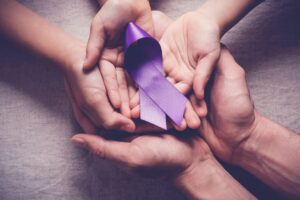 person holding purple ribbon for pancreatic cancer.